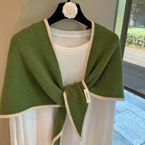 Detalle de chal de punto verde 100% lana con borde festoneado en color blanco crema