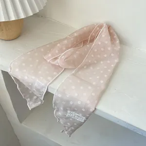 Detailansicht eines rosa gepunkteten Spitzenschals mit Markenetikett und feiner Textur