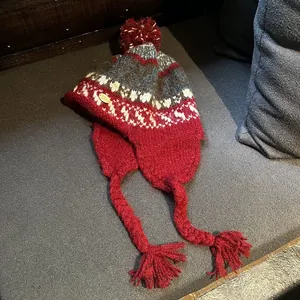 Détail du bonnet en tricot bordeaux avec motifs géométriques et étiquette en métal