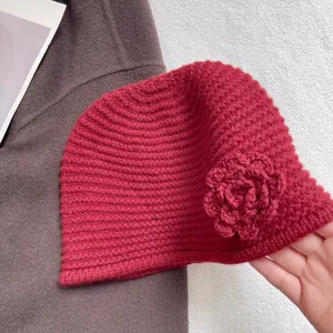 Detail of a deep red knit beanie with handcrafted crochet rose flower and ribbed texture