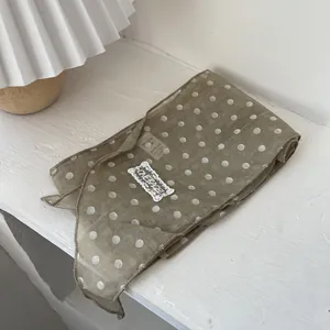 Detail eines Polka-Dot-Spitzenschals mit grüner Textur und dekorativem Patch