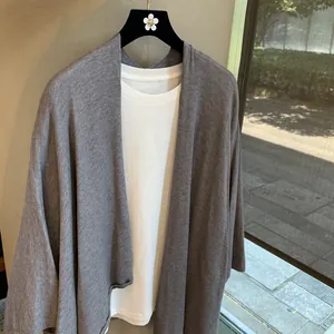 Detail of grey knit long-sleeve cardigan with white round neck inner shirt set