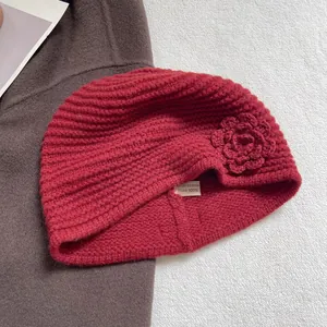 Detailed macro view of 100% wool red knit beanie with handmade crochet flower and wash label