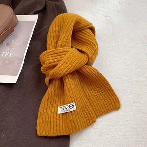 Close-up of ribbed ginger wool scarf with premium stitched brand label and texture