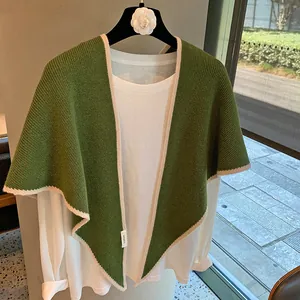 Detalle del chal de lana con textura de canalé y etiqueta 100% WOOL en una percha