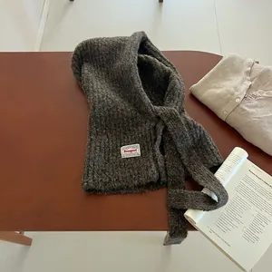 Detailed knit texture of a brown Balaclava hat with a white logo tag on wooden background