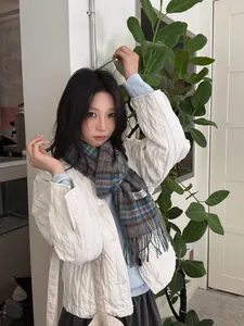 Detail of wool plaid scarf with fringes paired with a white quilted jacket for winter