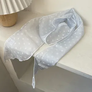 Detail eines hellblauen Polka-Dot-Chiffonschals mit zartem Stoff und gesäumten Kanten