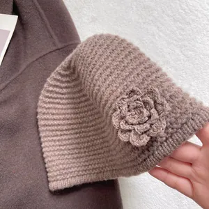 Detailed close-up of dark brown knit beanie with handmade crochet flower and ribbed texture