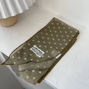 Nahaufnahme des olivgrünen gepunkteten Seidenschals mit Stickerei-Spitzenetikett