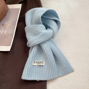 Detailed texture of light blue knitted wool scarf featuring a white woven brand label