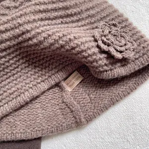 Macro detail of 100% wool knit hat showing crochet floral pattern and quality texture