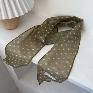 Detailansicht des olivgrünen Polka-Dot-Spitzenschals mit feiner Kantennaht und Etikett