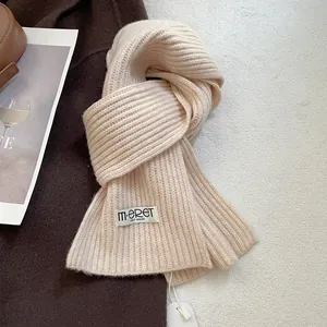Macro shot of beige knitted wool scarf texture with brand label and paper tag