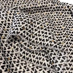 Linen feel scarf with gold foil and black heart patterns featuring frayed raw edges