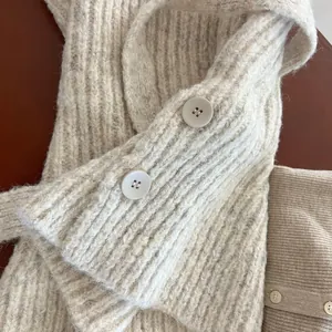 Detailed close-up of cream chunky knit texture and large buttons on wool cardigan