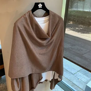 Brown knitted poncho layered over white T-shirt on floral hanger with a soft natural lighting