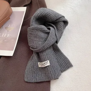 Close-up of gray ribbed knit wool scarf with brand label on life-style background