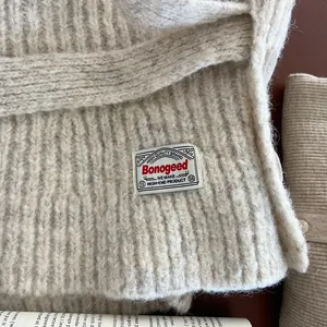 Close-up of beige wool knit texture with high-quality Bonogeed brand woven label