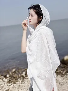 Close-up of white cotton linen shawl with delicate embroidery patterns and a hooded design