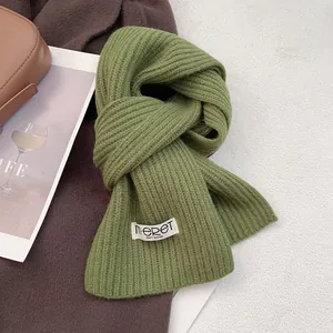 Close-up of grass green wool scarf with ribbed knit texture and white logo label detail
