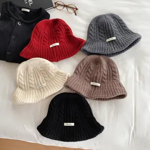 Flat lay of 100% Merino wool cable-knit fisherman hats in five assorted colors