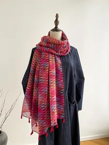 Dettaglio di sciarpa colorata a zig-zag con nappe rosse su un manichino da donna