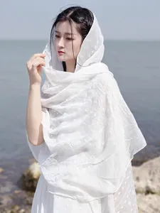 Detail of white cotton linen scarf with jacquard dots on a beach background