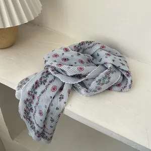 Detail of light blue floral pleated scarf with delicate pink patterns and zigzag edges