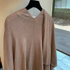 Detailed close-up of brown knit poncho texture and craftsmanship on a hanger