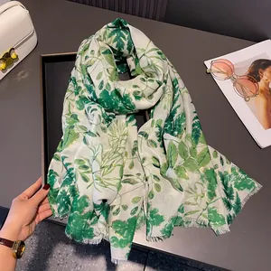 Macro detail of cotton linen scarf featuring green leaves and elegant gold foil accents