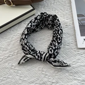Chic black and white leopard print silk scarf styled in a knot for neck or hair accessory