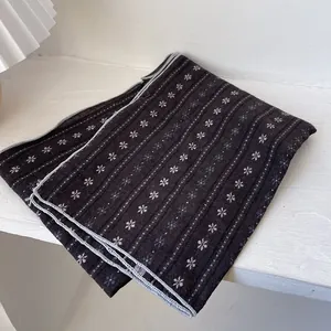 Close-up of double-sided cotton scarf with white floral print and gray stitched edges
