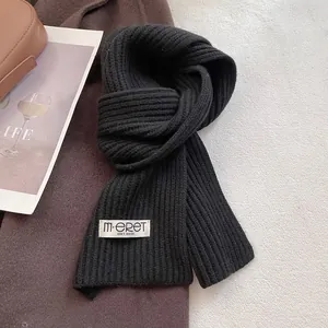 Detailed view of the black rib-knit wool scarf with a white woven brand label