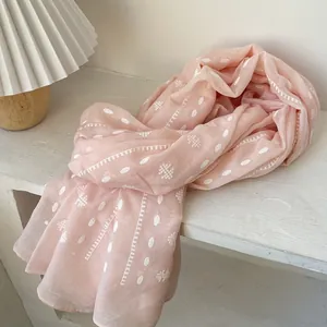 Close-up of pink linen scarf with white polka dots and floral patterns on wood