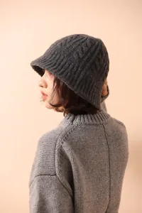 Close-up of dark grey merino wool knitted bucket hat featuring intricate cable knit texture