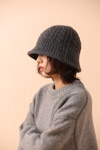 Detail showing the thick cable-knit texture of a dark grey merino wool cloche hat