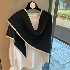 Detalle de chal de lana pura tejida con ribete crema mostrando la textura suave y fina