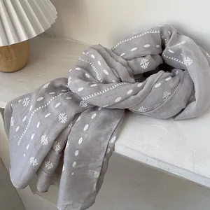 Close-up of lightweight grey cotton scarf with white embroidery and bohemian dot patterns