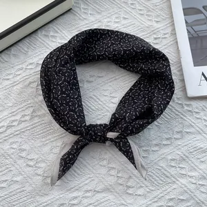 Detail of black silk blend square scarf with white paisley pattern and beige border knot