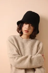 Detail of black merino wool fisherman hat with cable knit texture and beige sweater