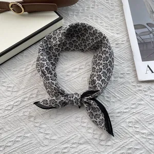 Elegant black paisley print silk cotton neck scarf styled on a minimalist backdrop