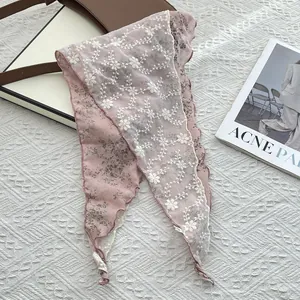 Detail of floral embroidery on pink linen scarf with delicate scalloped edges
