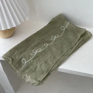 Macro detail of olive green cotton-linen scarf with white butterfly embroidery pattern
