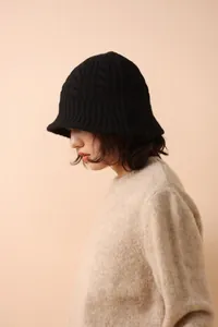 Detailed close-up of chunky knit merino wool texture on a black winter bucket hat