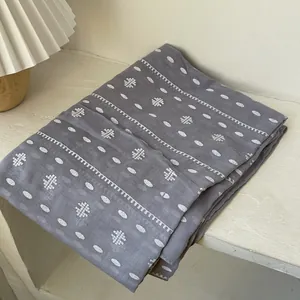 Detail of grey cotton linen scarf with white geometric folk embroidery texture