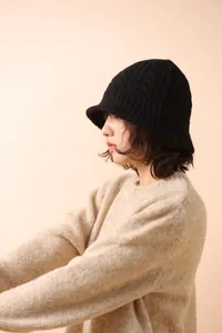Close-up of black merino wool bucket hat featuring thick cable knit texture and narrow brim
