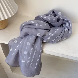 Detail of grey-purple linen scarf with white geometric ethnic pattern on display