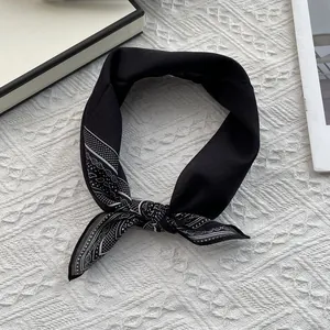 Detalle de pañuelo negro de seda y algodón con estampado paisley blanco en los extremos