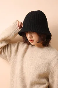 Detail of the black merino wool fisherman hat featuring a classic cable knit texture pattern